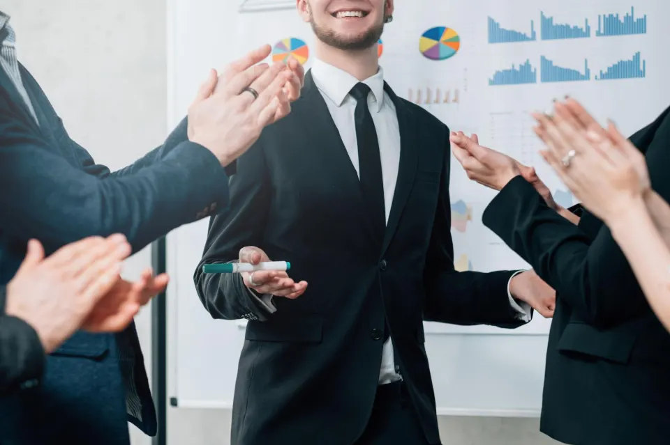 Colleagues applauding a presenter in front of a board of charts